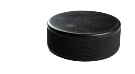 A single, dark hockey puck, angled, against a pure black background, displays its textured surface and minor imperfections.