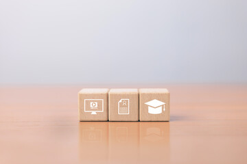 Wooden blocks with online learning icons, certificate and graduation cap symbolizing online learning, digital education.