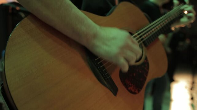 Man playing guitar on music stage in dark, musician, close-up