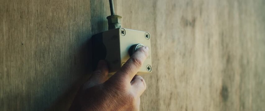 Finger pressing button on control panel inside wooden shooting stall