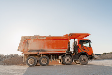 Obraz premium Large orange dumper truck carrying stones in a quarry