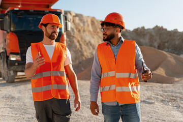 Engineers discussing next steps at construction site with dumper truck in background