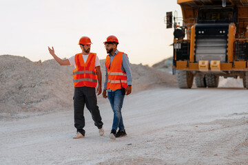 Engineers walking and discussing in quarry next to dumper truck © Maria Vitkovska