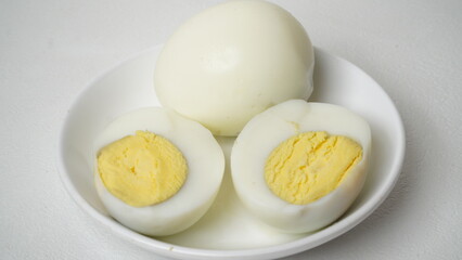 Peeled boiled eggs served on a white plate with a white background