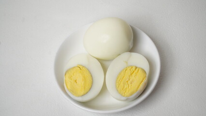 Peeled boiled eggs served on a white plate with a white background