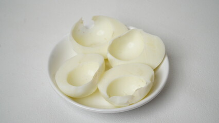 Peeled boiled eggs served on a white plate with a white background