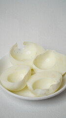 Peeled boiled eggs served on a white plate with a white background