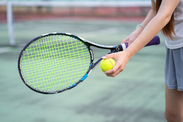Person holding tennis racket and ball on court, ready to serve