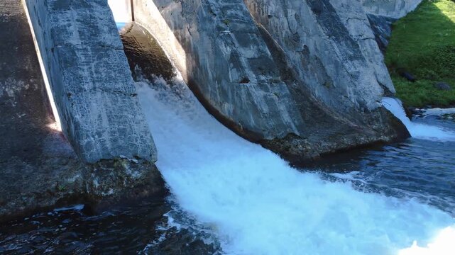 Close-up view of the overflow water discharge from an old, end-of-life concrete dam controlling the level of a forest lake. Mitis Dam, Quebec, Canada, 2025.