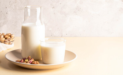 Pistachios on plate with glass and bottle of alternative nut milk, showcasing healthy lifestyle