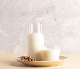 Milk and pistachios arranged on beige plate with textured background for healthy lifestyle concept