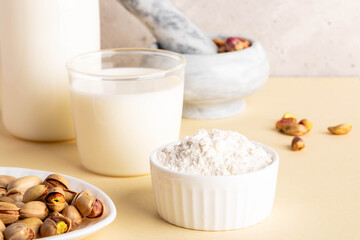 Pistachios, milk, nut flour and nutty milk in bright kitchen setting with natural light and textures