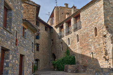 Narrow cobblestone streets in Ainsa with a view of the Romanesque church and medieval tower in one of the most beautiful villages in Spain
