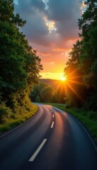 Sunrise paints the empty asphalt road winding through a vibrant green forest , empty, peaceful