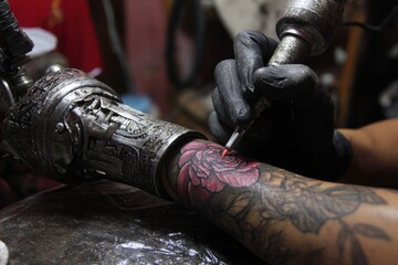 Tattoo artist applying rose design on arm