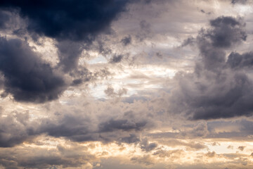 Dramatic cloudy sky with sun rays through dark and yellow clouds