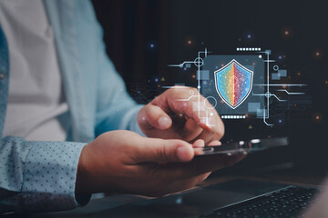 Businessman using smartphone activating digital shield security system with digital lock icon graphic overlay, innovative internet technology and mobile banking security concept