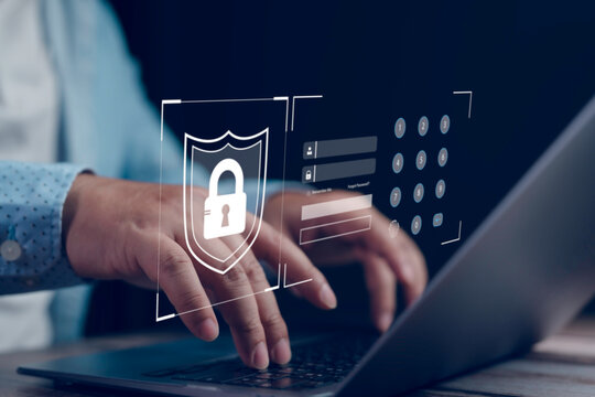 Office worker is securing computer data by typing password and using a shield icon, enhancing cybersecurity and protecting sensitive information in digital environment
