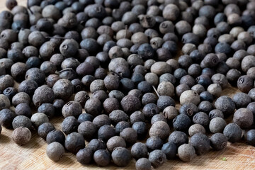 A bunch of black and brown seeds are spread out on a wooden table