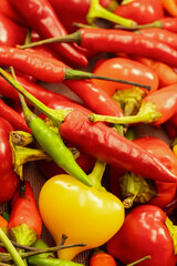 red peppers and yellow peppers are piled. The peppers are of different sizes and colors.
