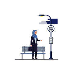 Woman in hijab waiting at bus stop with bench and street light.