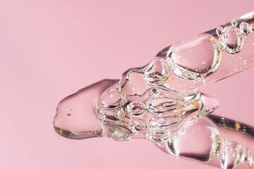 Pipette with serum, gel, oil or other cosmetic product on pink background. Macro closeup