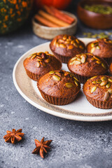 Autumn pumpkin cupcakes or baked muffins with fresh pumpkin and pumpkin seeds for Thanksgiving day vertical photo