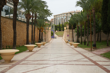 Benidorm, Spain – September 7 2025: Beautiful palm tree promenade and stone walls in urban park setting