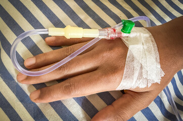 A patient’s hand with an intravenous (IV) line inserted