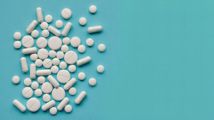 White Pharmaceutical Pills on Turquoise Background – Top View Medical Tablets and Medication Concept Photo