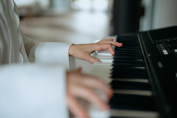 A person is seated at a piano, skillfully playing a melody. Soft lighting fills the room, creating an inviting atmosphere for a casual music session.