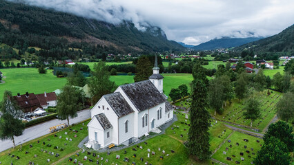 Overlooking the picturesque Stryn valley, the charming white church stands amidst rolling green...