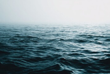 Fototapeta premium Deep blue ocean waves with white mist above, suggesting a calm and serene seascape with cool hues and a tranquil, atmospheric ambience