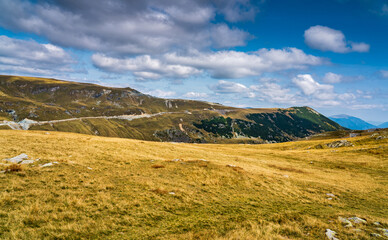 Obraz premium A solo traveler experiences a breathtaking autumn day in the wild Carpathian Mountains, near Lake Galcescu, in the Parang Mountains of Romania, where vibrant fall colors meet rugged peaks