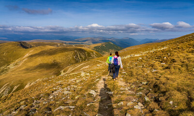 Fototapeta premium A solo traveler experiences a breathtaking autumn day in the wild Carpathian Mountains, near Lake Galcescu, in the Parang Mountains of Romania, where vibrant fall colors meet rugged peaks