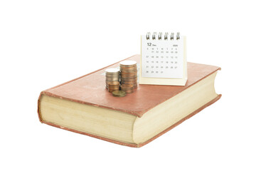 Book with coins and calendar showing December 2025 symbolizing financial planning and savings.
