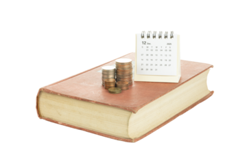 Book with coins and calendar showing December 2025 symbolizing financial planning and savings.