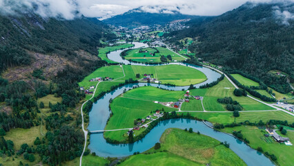 Stryn valley presents stunning views with winding rivers carving through vibrant green fields under...