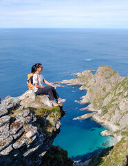 A traveler sits at the edge of Matind Mountain, enjoying stunning views of the deep blue sea and...