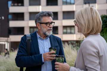 Diverse business couple having coffee and chatting outdoors during break