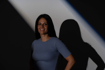 Naklejka premium Low key portrait of smiling mature woman with geometric gobo shadow on dark background
