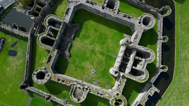 Aerial view of  the medieval ruins of Beaumaris Castle and the coastal town of Beaumaris on the Isle of Anglesey in Gwynedd off the north Wales coast. The castle dates from around 1295.