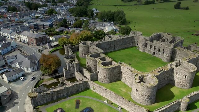 Aerial view of  the medieval ruins of Beaumaris Castle and the coastal town of Beaumaris on the Isle of Anglesey in Gwynedd off the north Wales coast. The castle dates from around 1295.