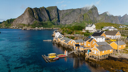 Colorful rorbu cabins line the waterfront in Sakrisoy, Lofoten, Norway, set against dramatic peaks...