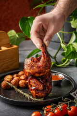 Hand holding grilled barbecue chicken with sauce