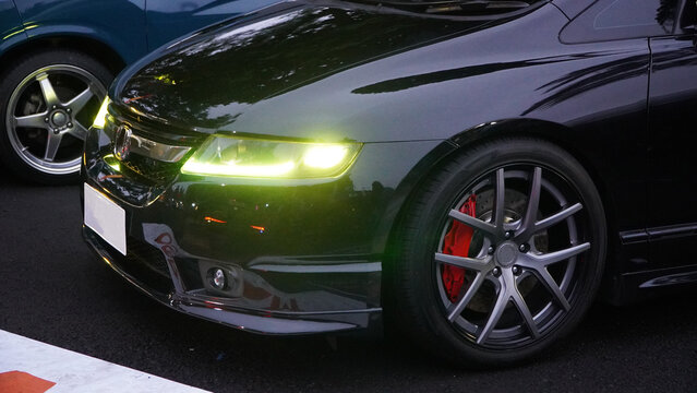 Wonosobo, Indonesia - 30 August 2025: Sleek modified sports car with glowing green fog lights and red brake calipers, aggressive front bumper detail.