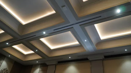 Fototapete Hotel Chic A wide-angle, upward-looking shot of a modern, coffered ceiling design featuring recessed square panels with warm LED cove lighting and integrated recessed spotlight fixtures.  © anungcamui