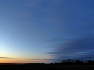 Long Exposure Landscape of a Field Under a Blue Twilight Sky - Minimalist View of a Dark Horizon with Streaky Clouds from Long Exposure