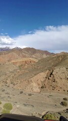 Mountainous landscape with varying hues of brown and a partly cloudy sky