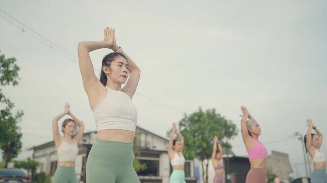 Women stretching tall in a standing yoga pose during a peaceful outdoor class in the early morning light